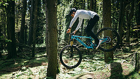 Ein Mann auf dem YETI MTe E-Bike im Wald zwischen 2 Bäumen