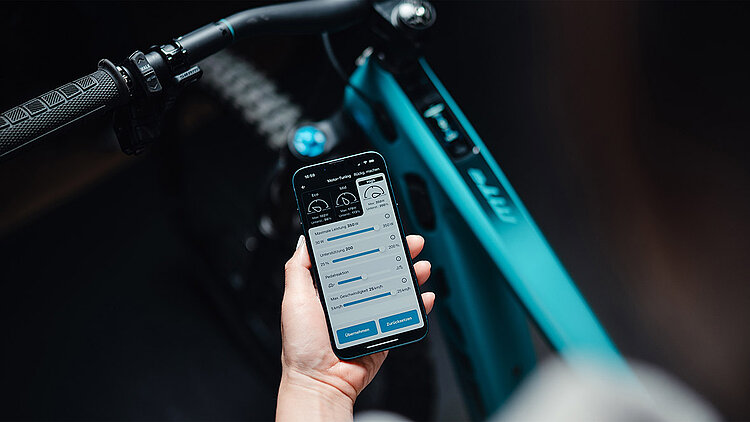 Smartphone mit TQ E-Bike App und Bike im Hintergrund