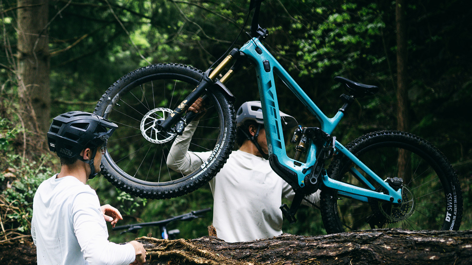 Mountainbike wird über einen Baumstamm gehoben