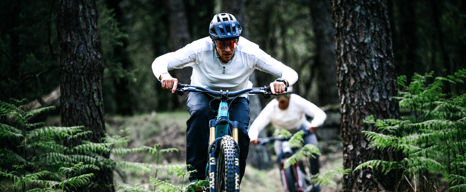 Zwei E-MTB Fahrer hintereinander im Wald