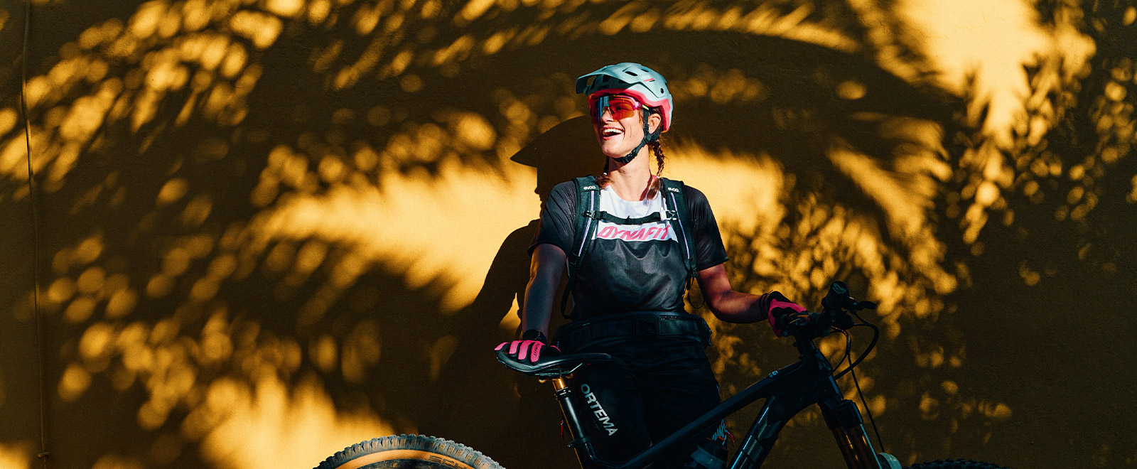 Steffi Marth im Bike-Outfit vor gelber Wand mit Schatten